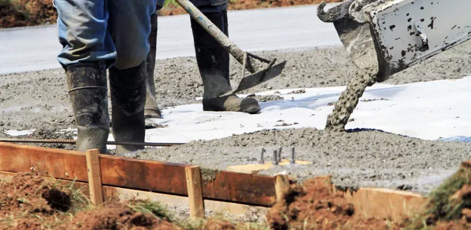 A man is pouring concrete into a hole in the ground.
