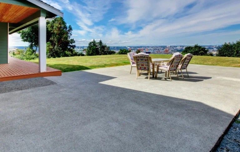 A patio with a table and chairs in front of a house.