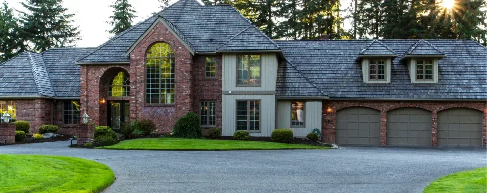 A large brick house with three garages and a driveway.