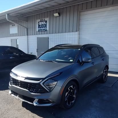 Grey Kia SUV parked outside a building with the business name 