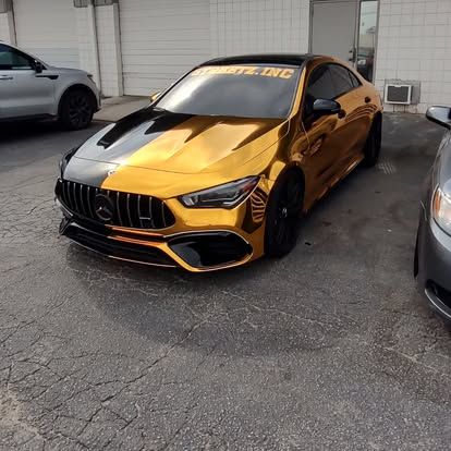 Gold and black Mercedes-Benz car parked on asphalt, front partially in shadow, 