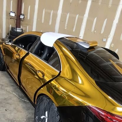 Gold and black car with partially wrapped body in a garage setting.