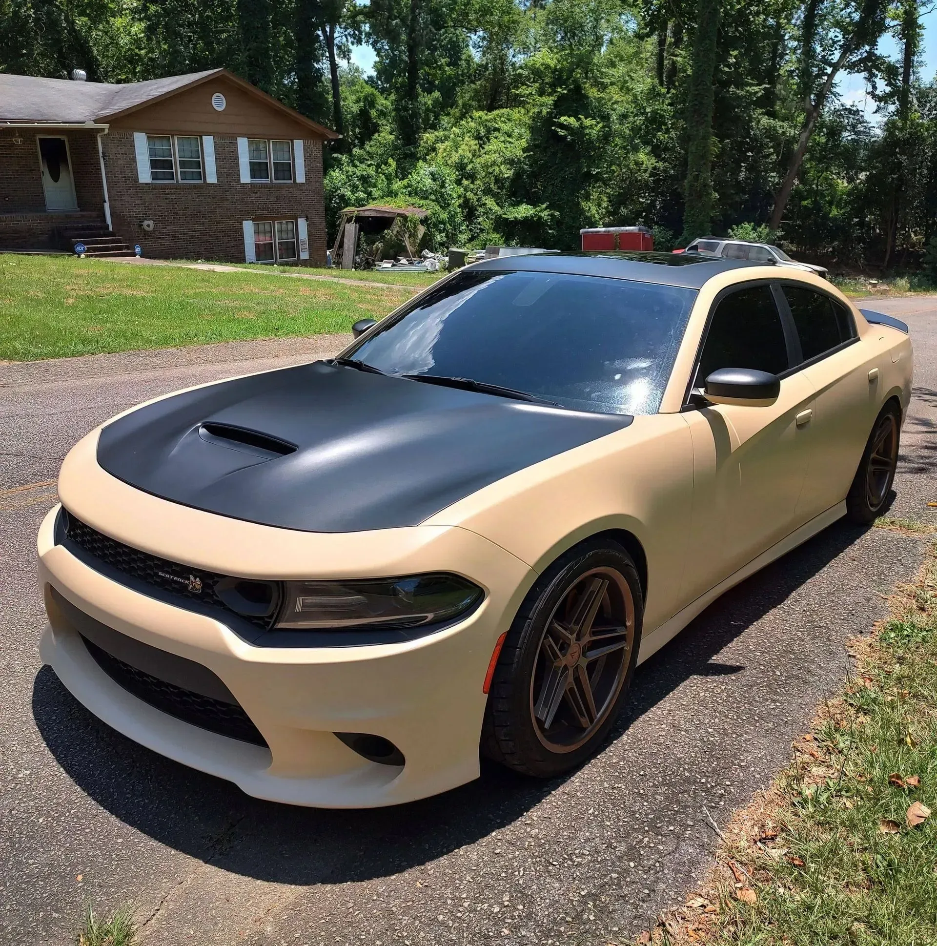 Tan Dodge Charger with a black hood and roof parked on a driveway.