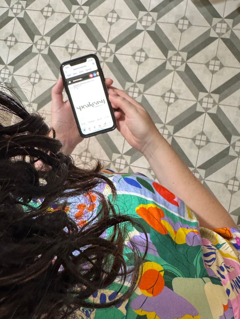 woman looking at phone with encaustic green tiles on floor