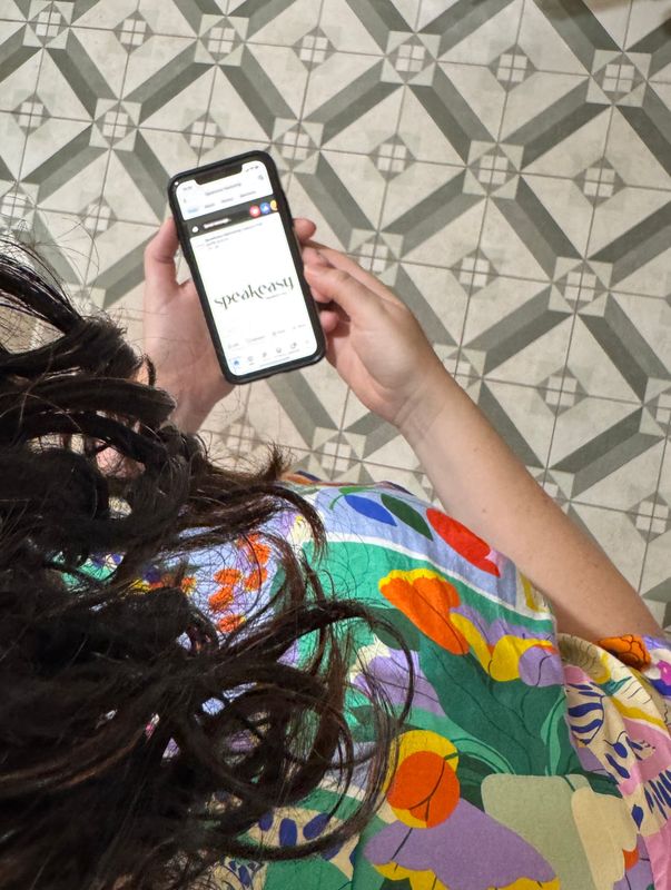 woman looking at phone with encaustic green tiles on floor