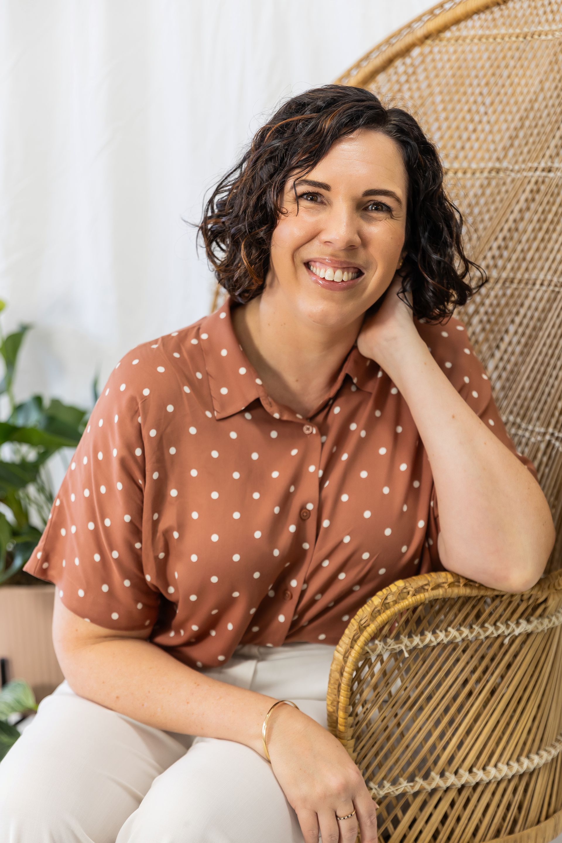 sarah dummer sitting on chair in spotted shirt