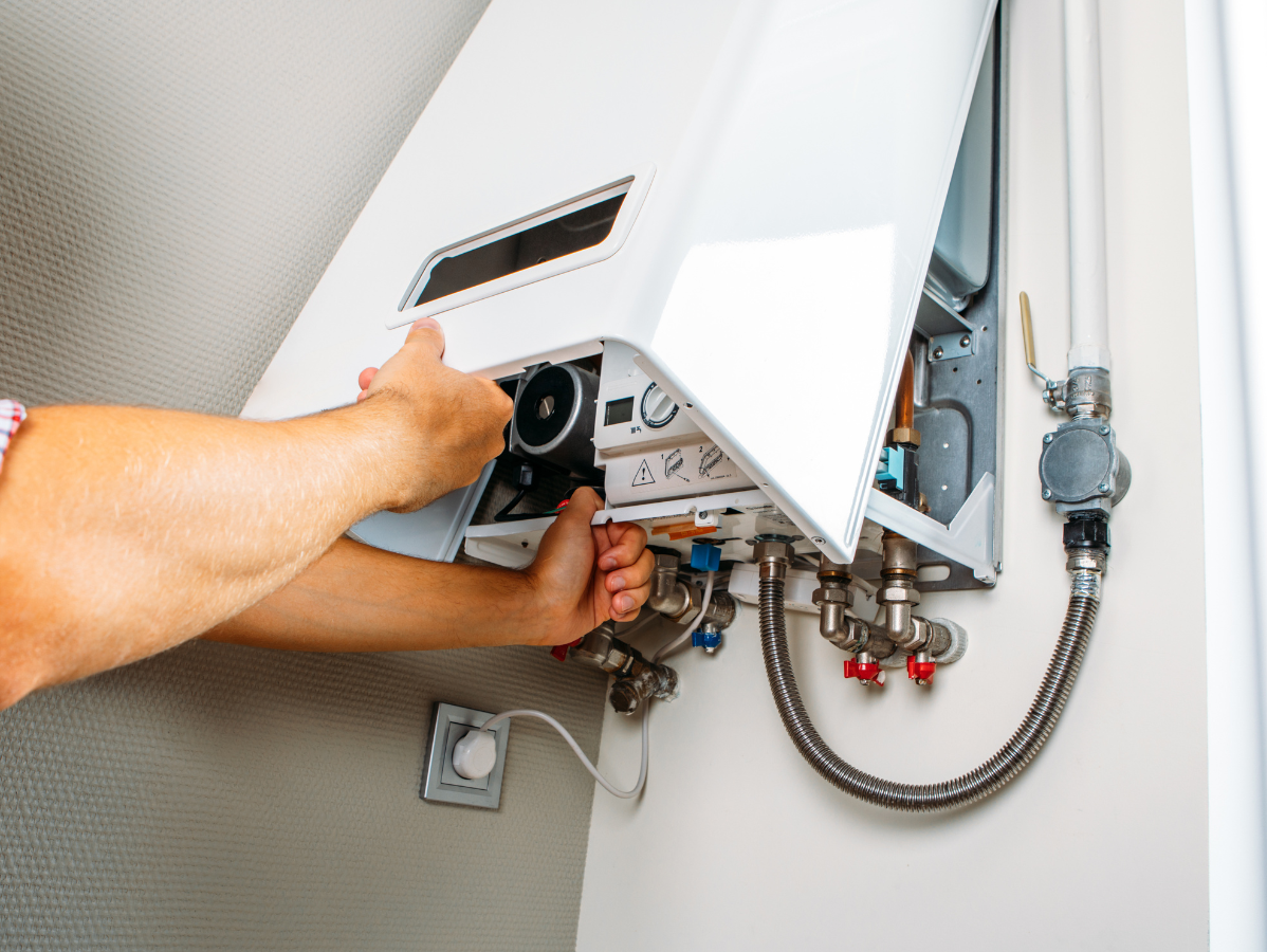 Hands adjusting a white wall-mounted furnace. Close up view; interior.