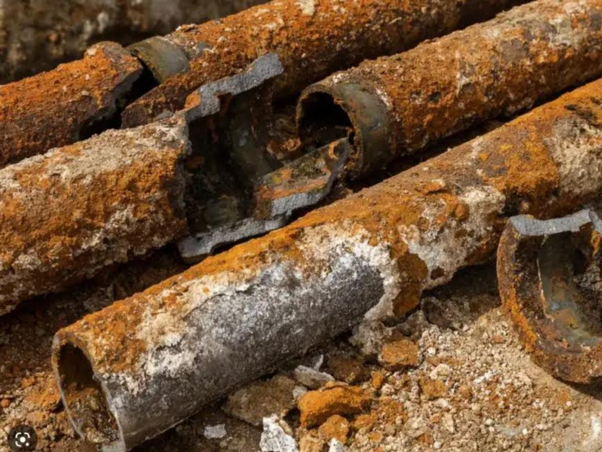 Severely corroded and cracked water pipes covered in rust.