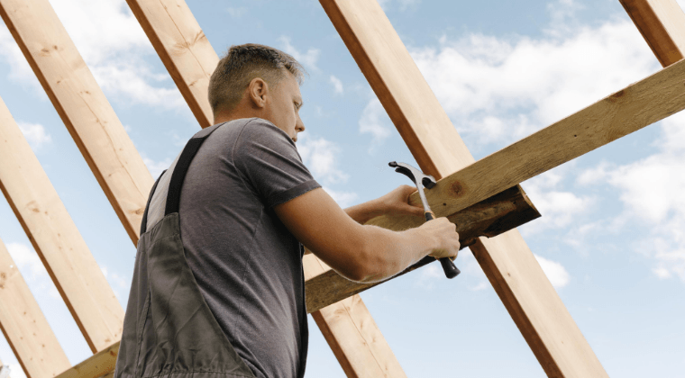 A man is working on a roof with a hammer and a wrench.