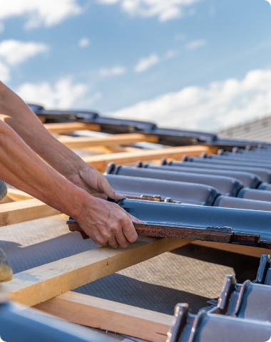 A man is installing tiles on a roof.