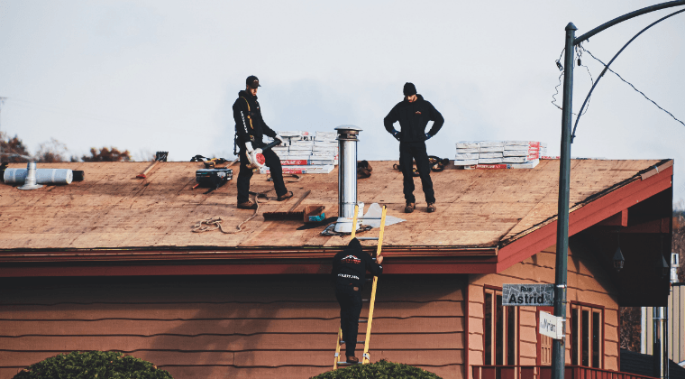 Three men are working on the roof of a house.