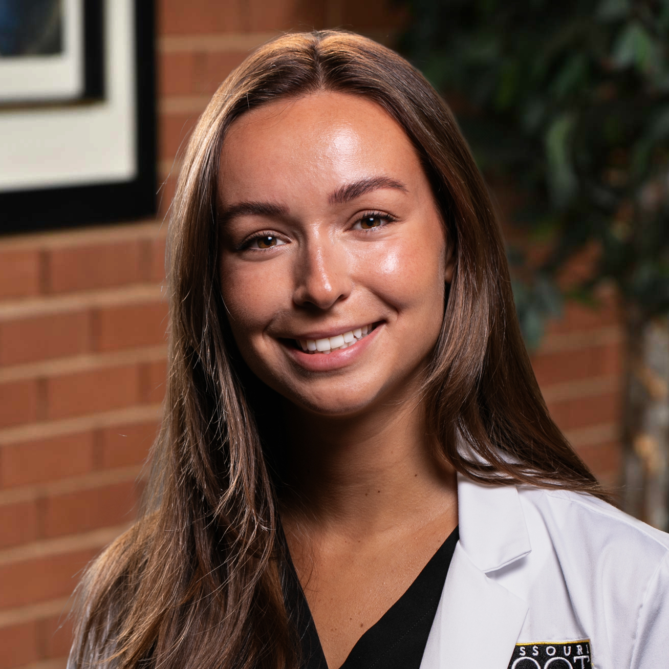 A smiling doctor in a lab coat with a stethoscope around his neck.