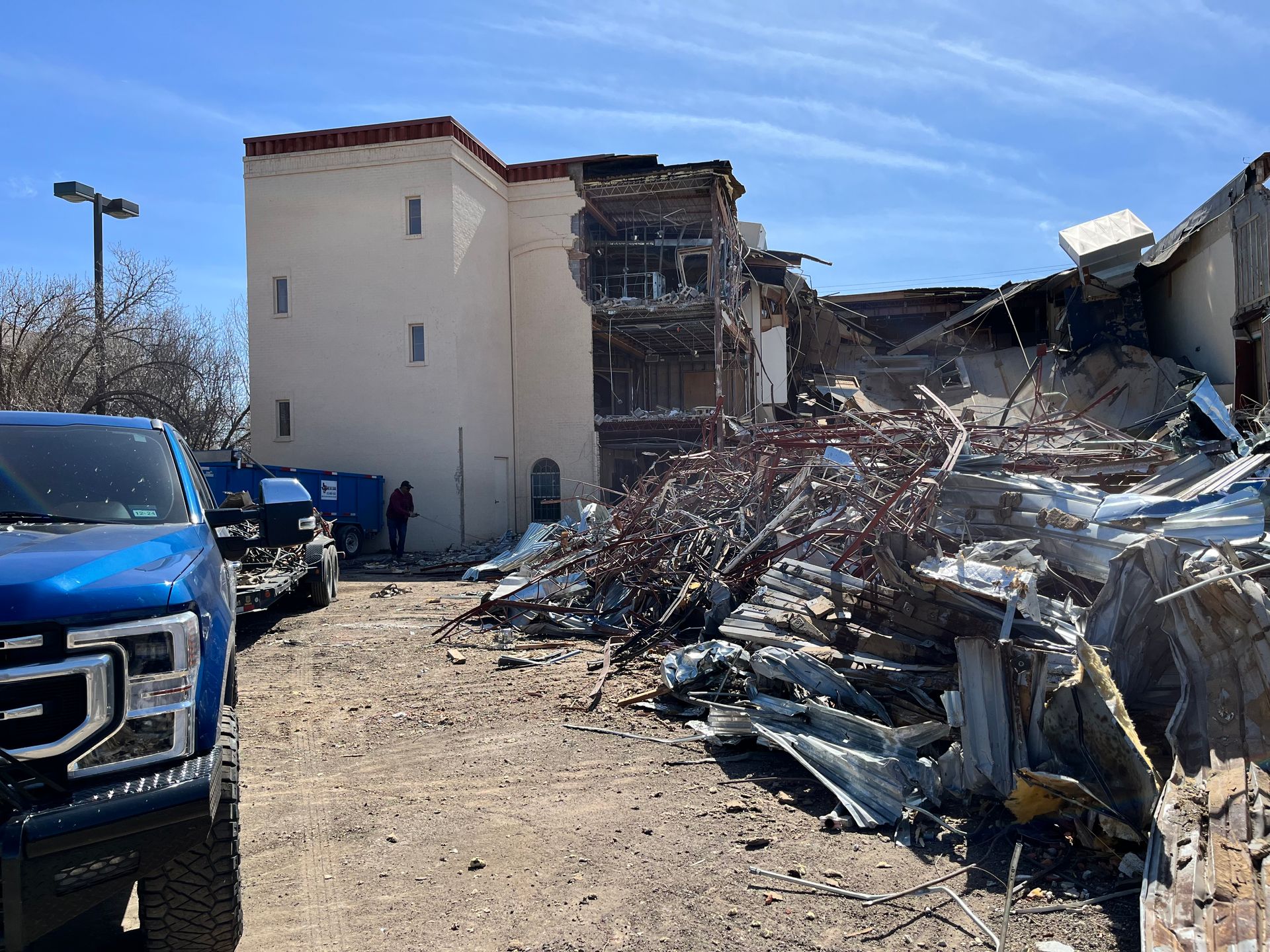 a blue truck is parked in front of a building that is being demolished .