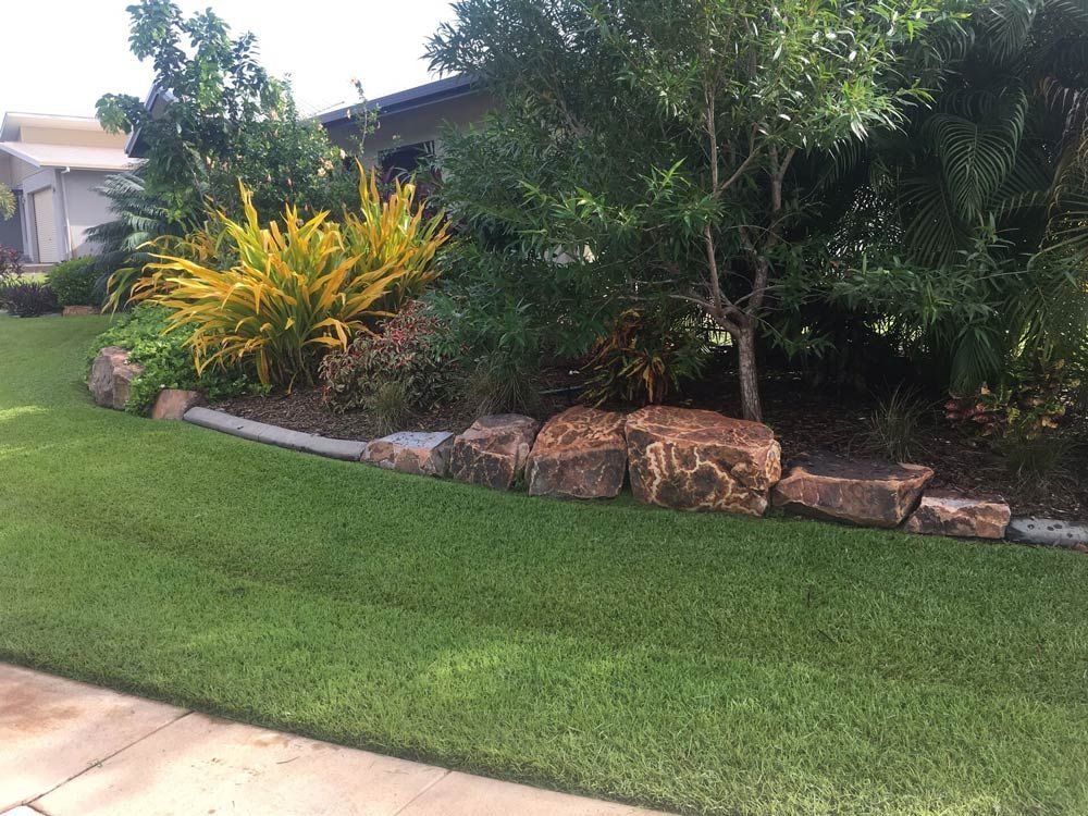 A Lush Green Lawn with Rocks and Trees in Front of A House — Green Vision NT in Palmerston, NT