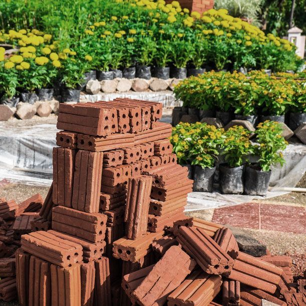 A Pile of Bricks Is Sitting in Front of A Garden Filled with Potted Plants — Green Vision NT in Palmerston, NT