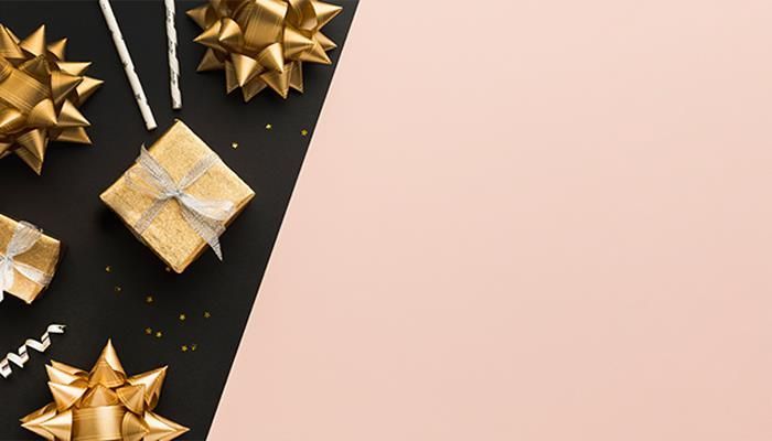 Gold gifts, bows, and confetti on black and pink background.