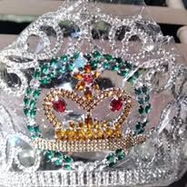 Sparkly silver crown with green, gold, and red gemstones and a central crown emblem
