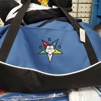 Blue and black duffel bag with a star logo, resting on a store shelf.