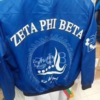 Blue jacket with “Zeta Phi Beta” embroidered on the back in white and silver.