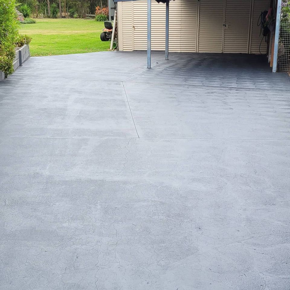 A Concrete Driveway With a Garage in the Background — Dave Smith Concrete in Salt Ash, NSW