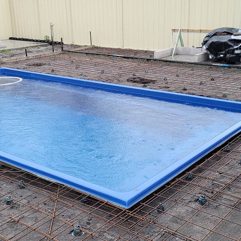 A Blue Swimming Pool is Being Built in a Backyard — Dave Smith Concrete in Newcastle, NSW
