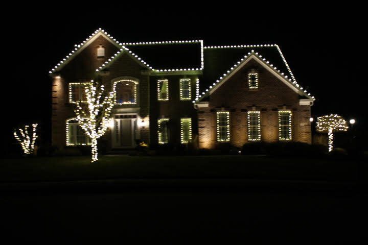 A large house is lit up with christmas lights at night