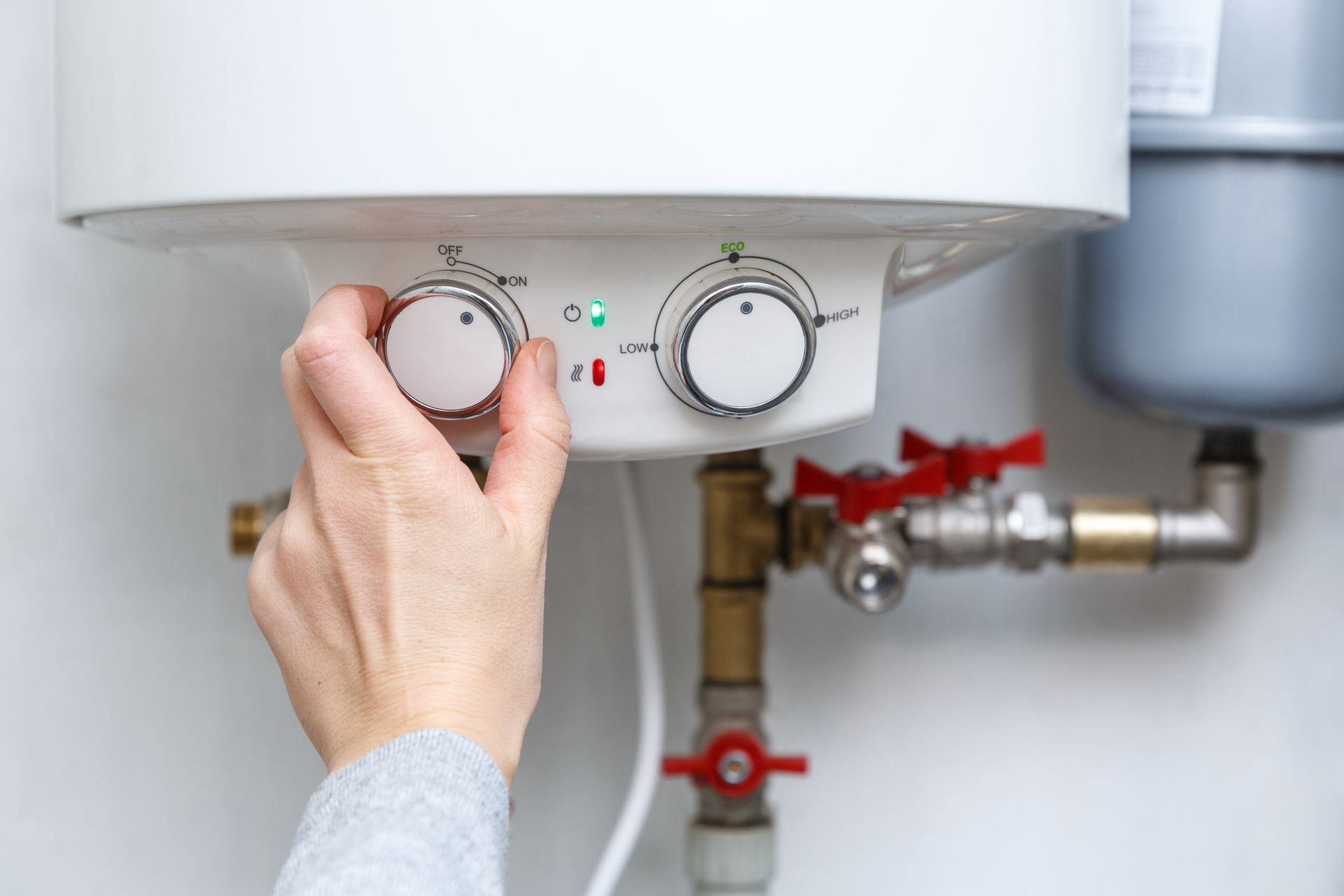 A person is adjusting the temperature of a water heater.