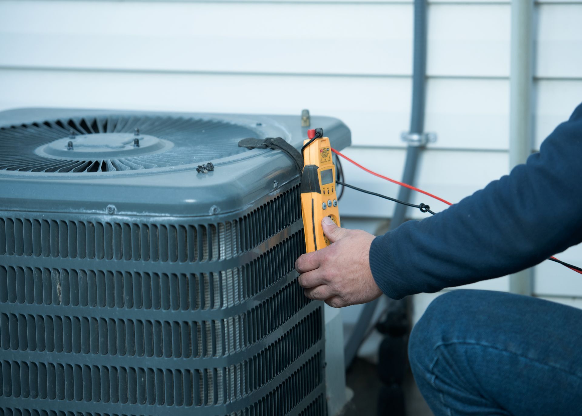 A man is working on an air conditioner with a clamp.