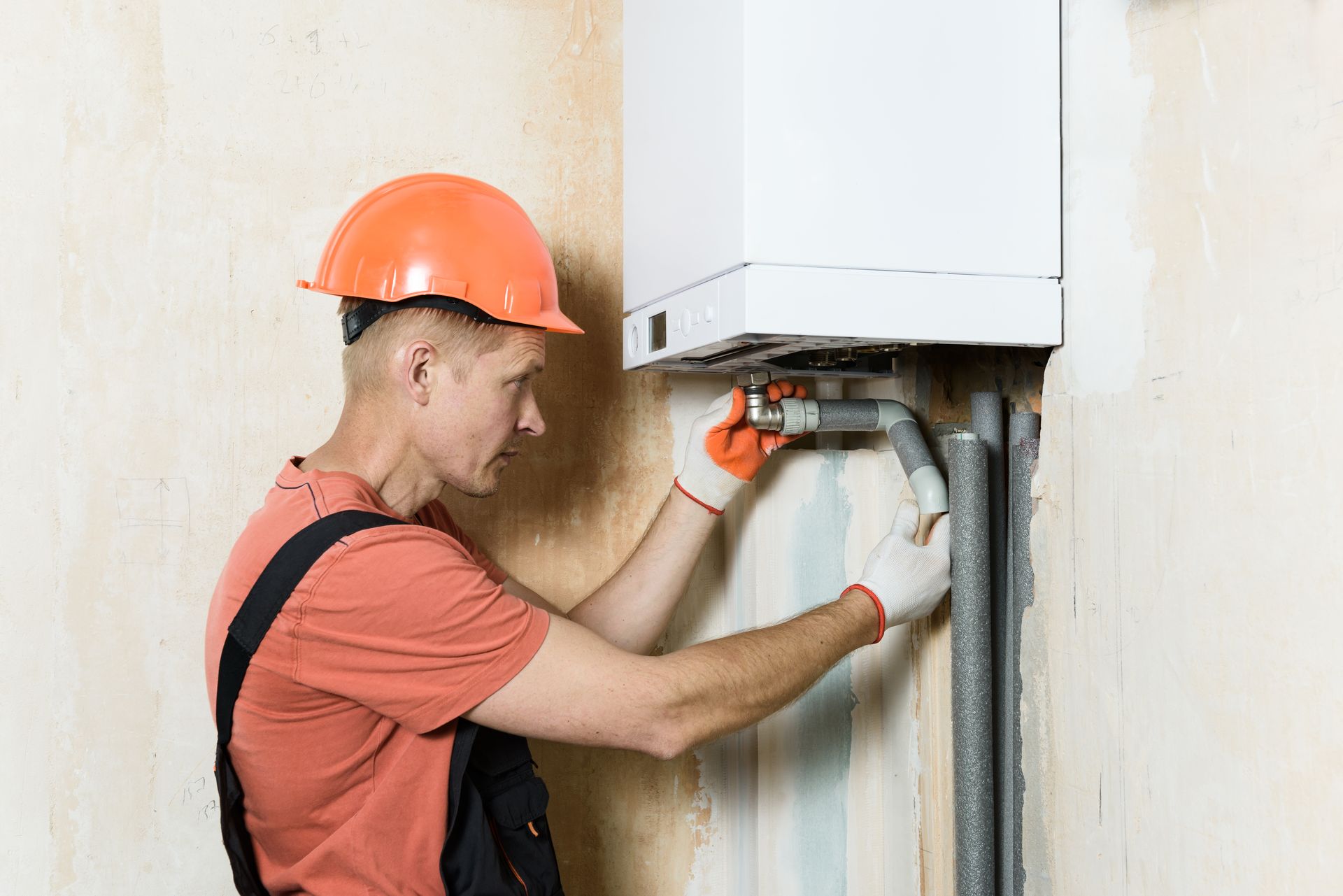 A man is installing a boiler on a wall.