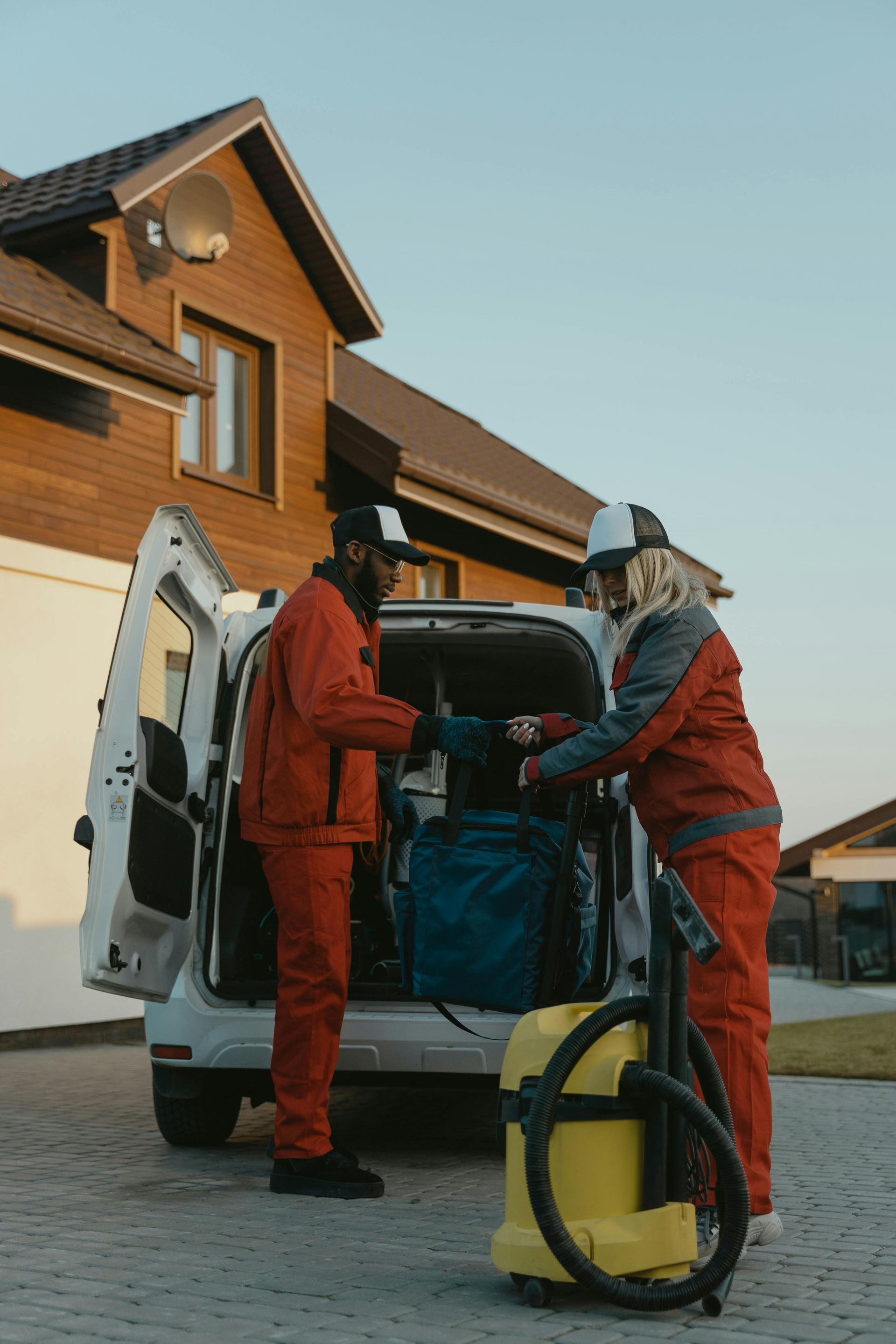 A man and a woman are loading a vacuum cleaner into the back of a van.