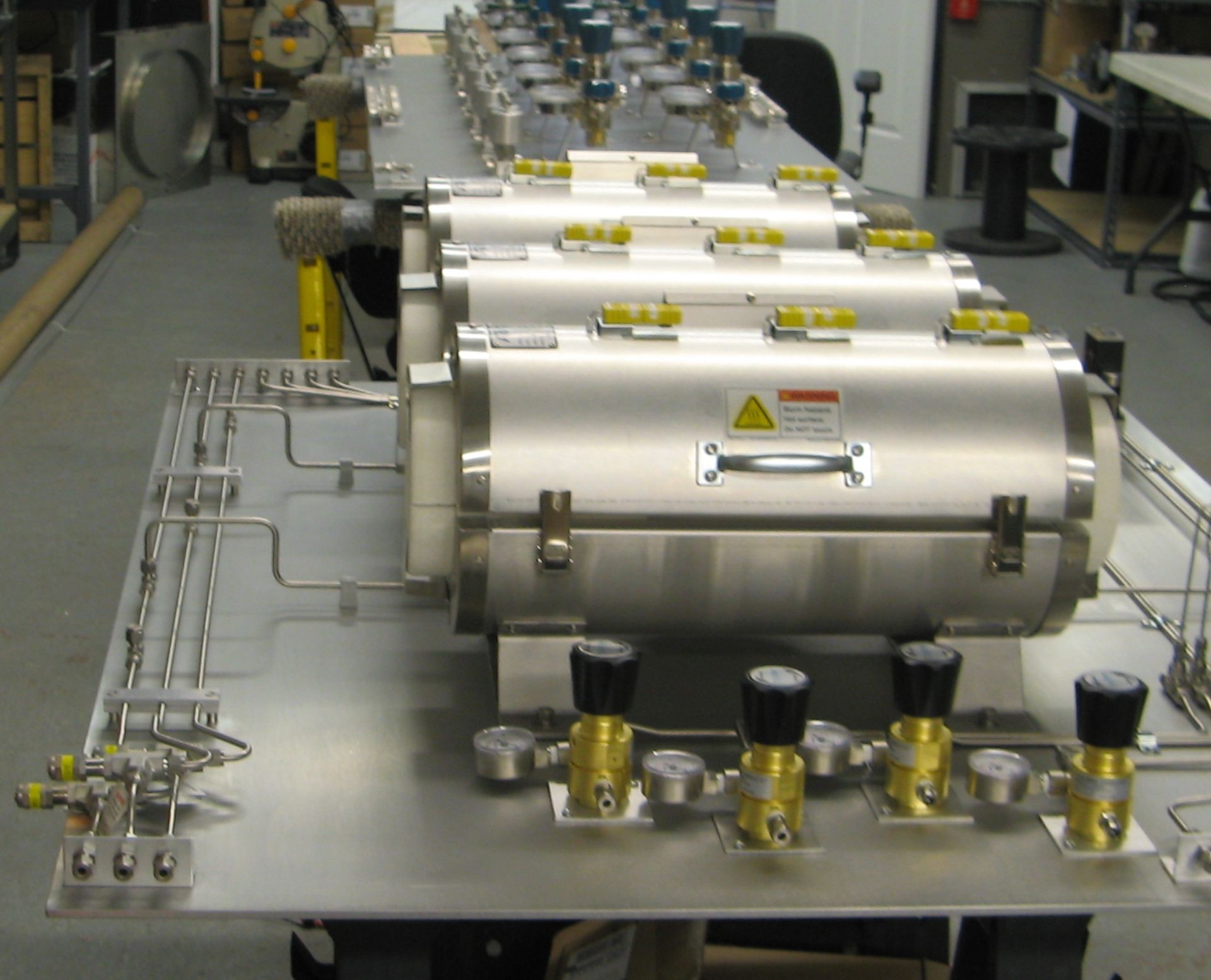 A row of stainless steel cylinders are lined up on a table
