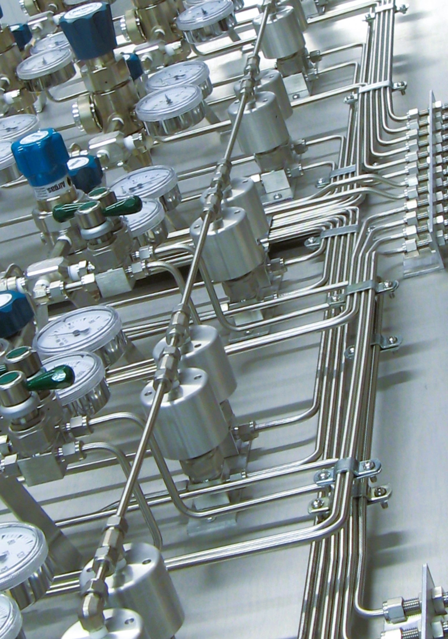 A bunch of gauges and pipes are lined up on a wall