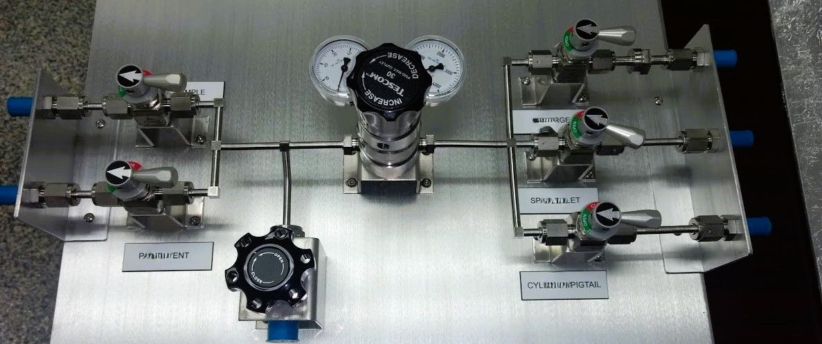 A metal box with a bunch of valves and gauges on it.