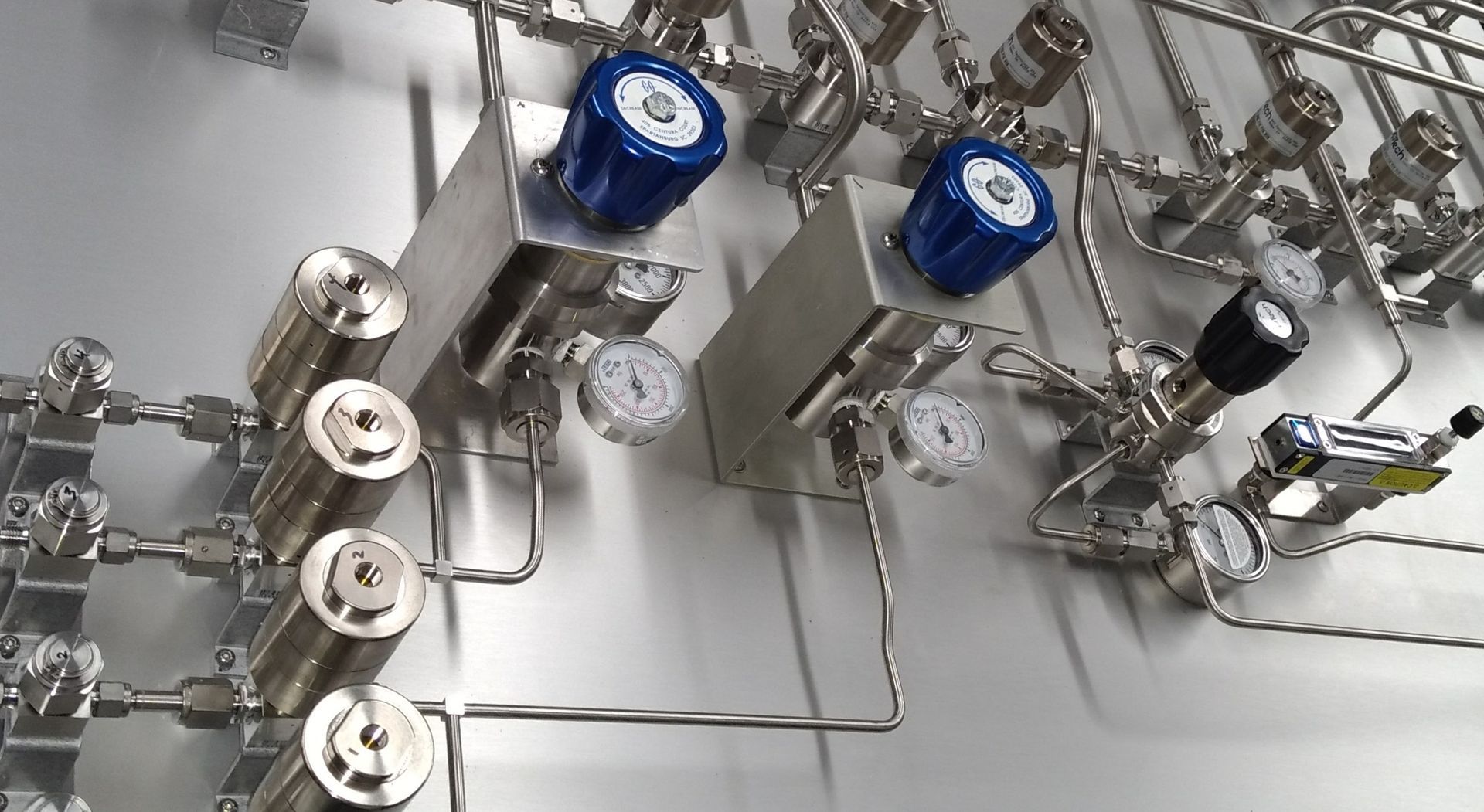 A bunch of stainless steel pipes and valves on a wall.