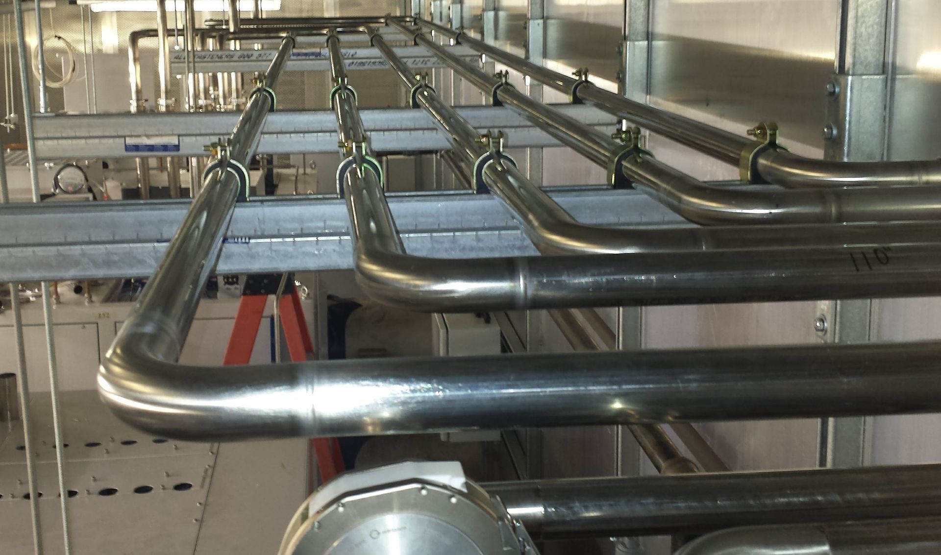 A row of stainless steel pipes hanging from the ceiling of a building.
