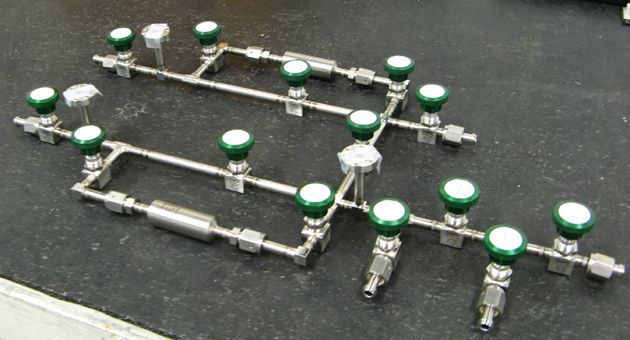 A stainless steel pipe with green knobs is sitting on a black surface.