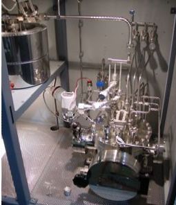 A machine is sitting inside of a room with a lot of pipes.