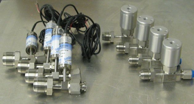 A bunch of stainless steel valves are sitting on a table