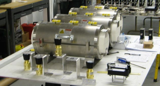 A row of stainless steel tanks are sitting on a table