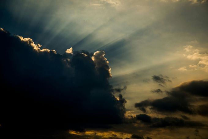 Sunlight breaking through dark, cloudy sky.