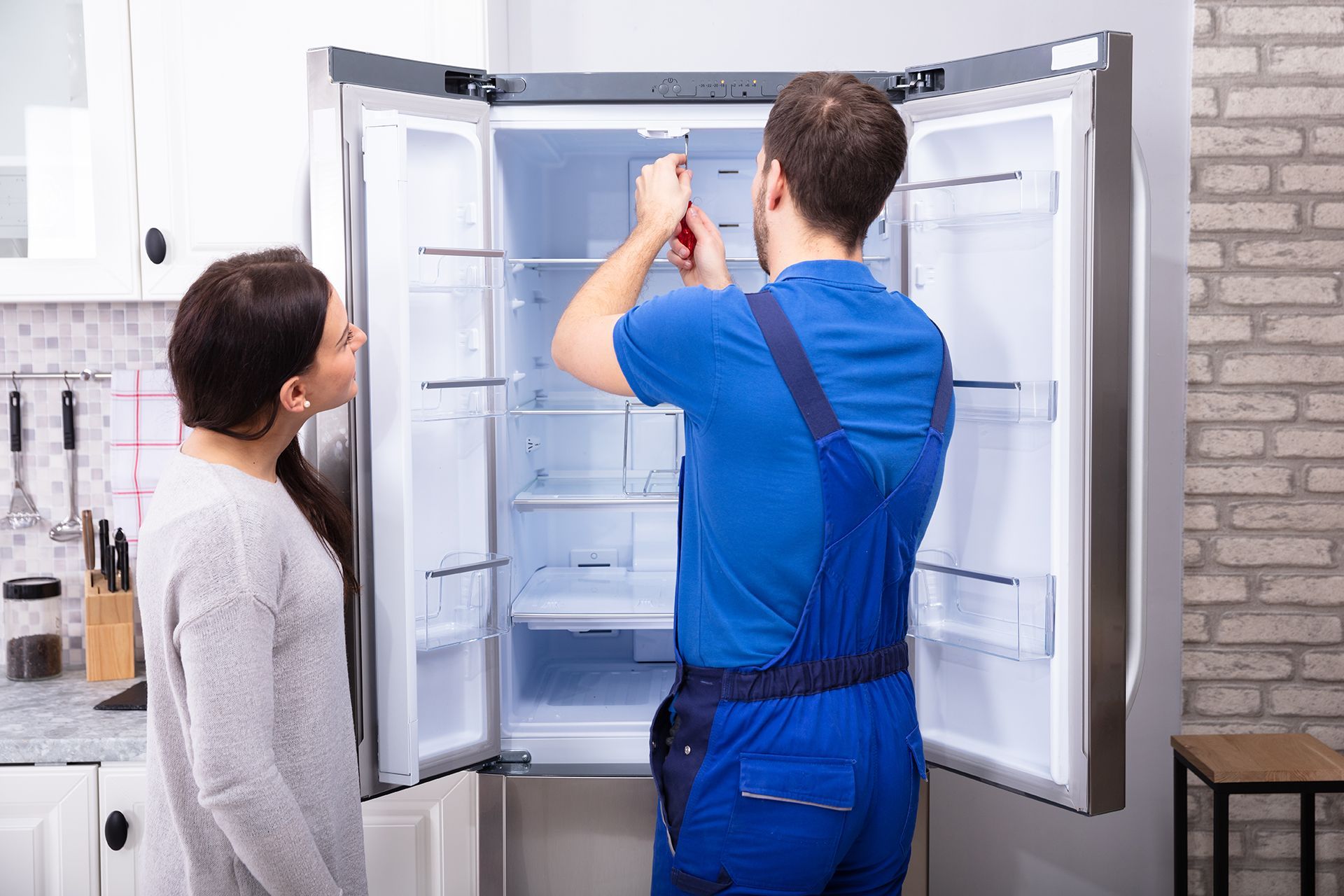 Repair Man Repairing Refrigerator With Client