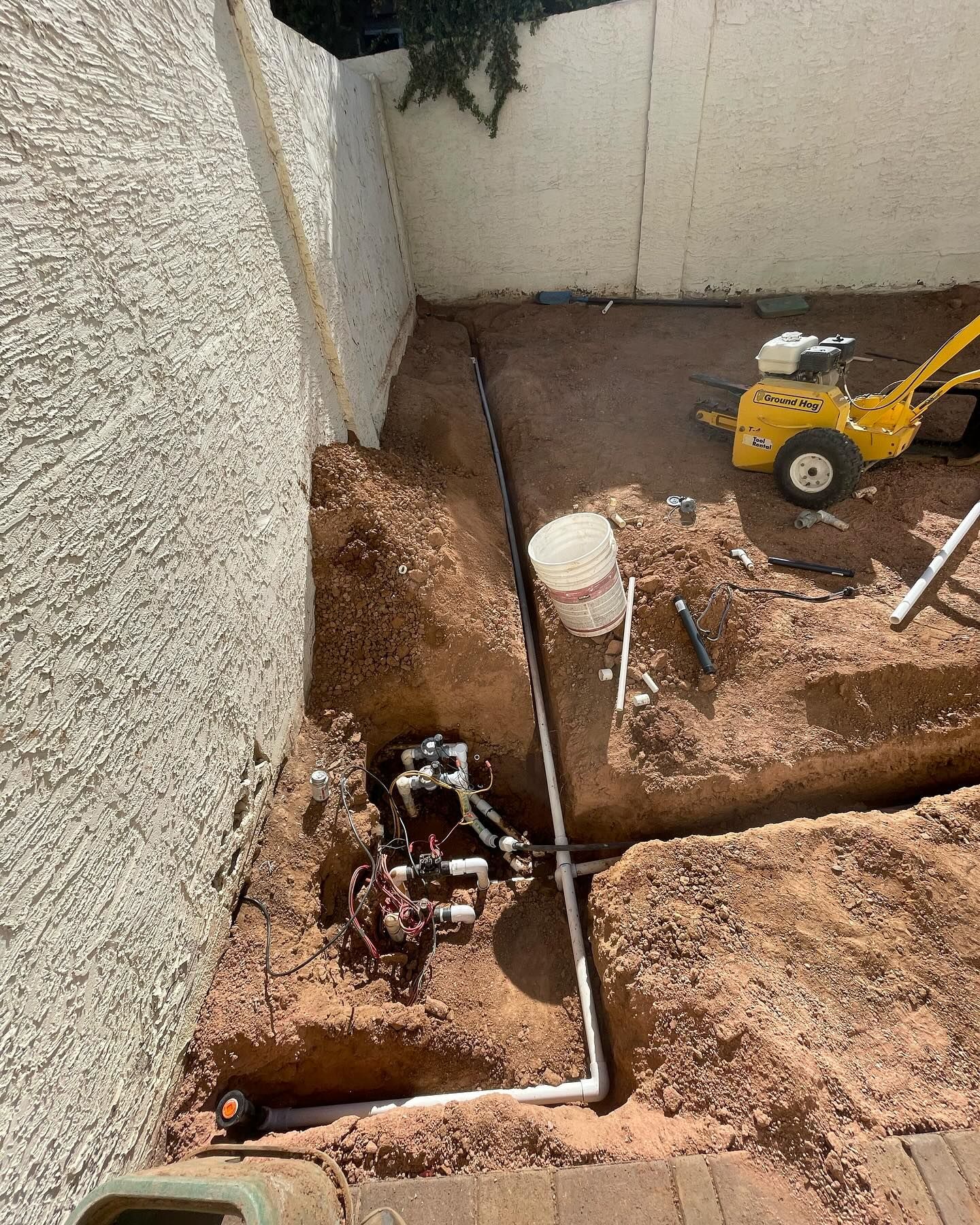 Irrigation system installation in progress, showing pipes, valves, and soil.
