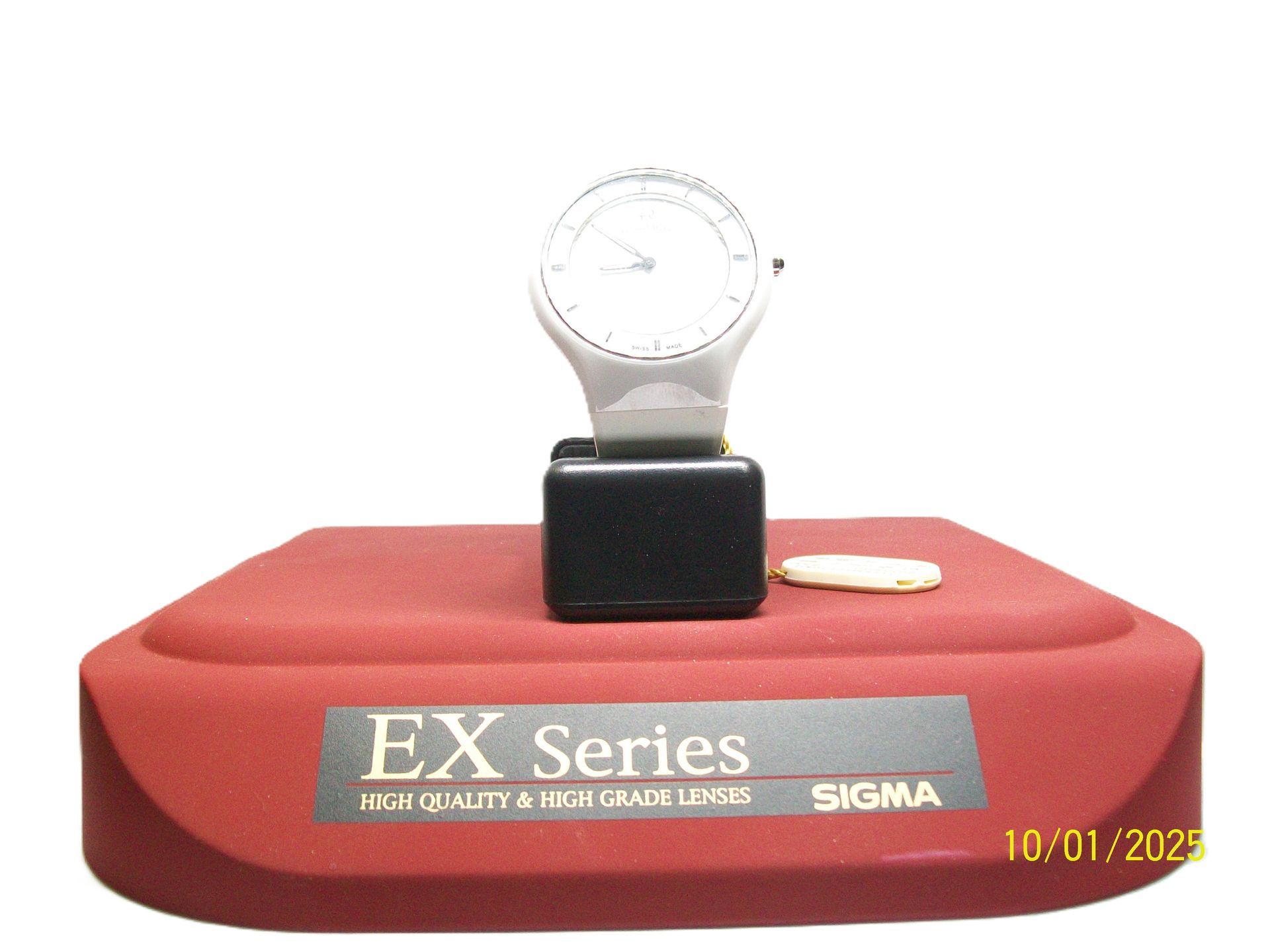 Een hoogwaardige meter uit de Sigma EX-serie op een rode displayvoet met een zwart blok en een witte achtergrond.