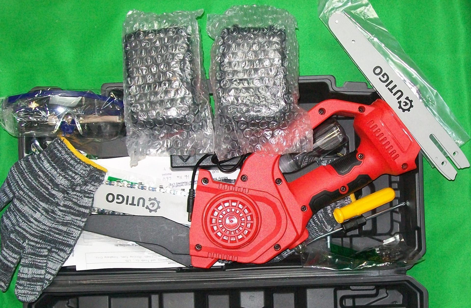 Rode en zwarte handkettingzaag in een zwarte koffer met handschoenen, extra zaagblad en veiligheidsbril.