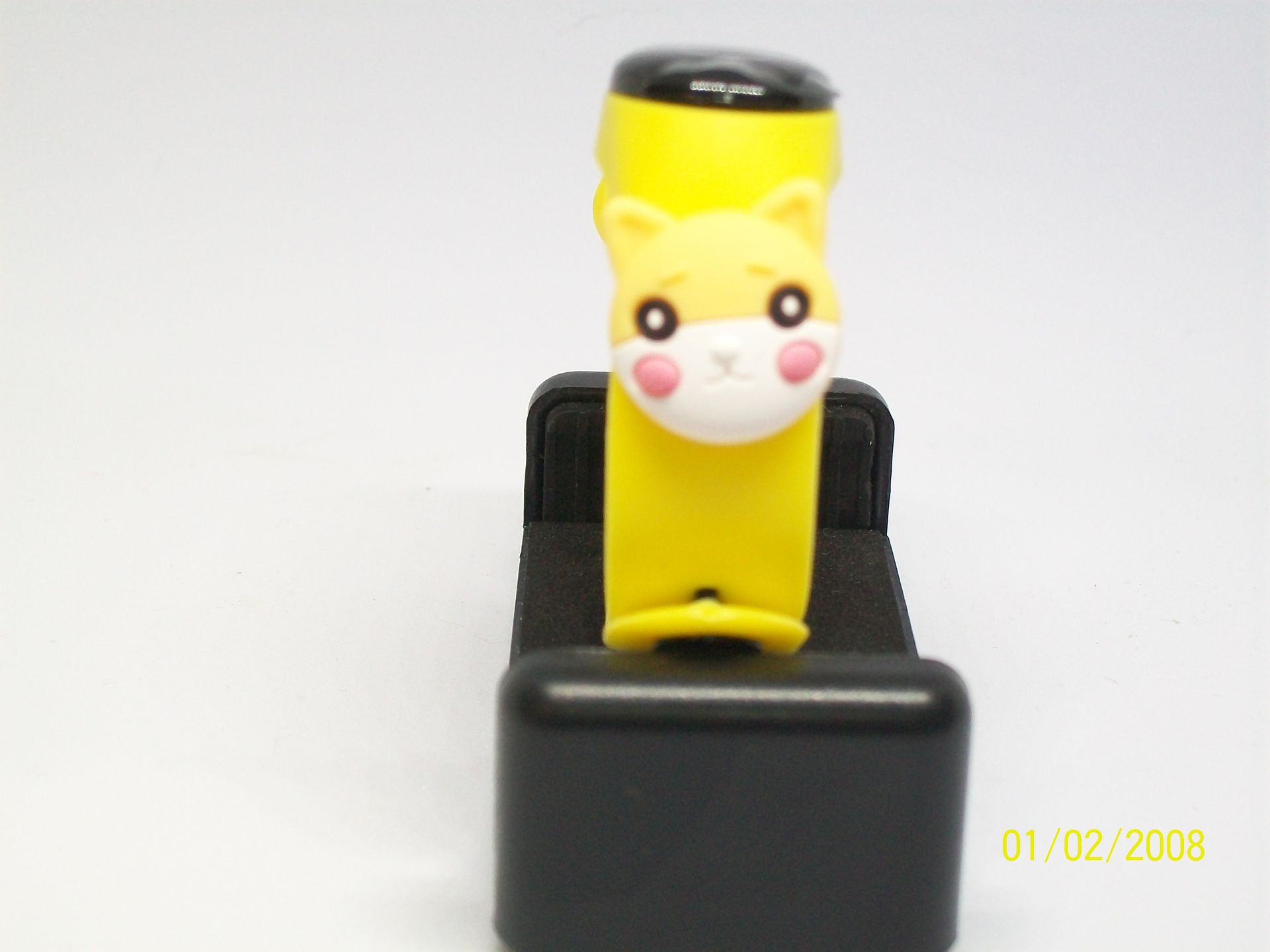 Oranje fitnesstracker met wit bedeltje op een rood doosje.