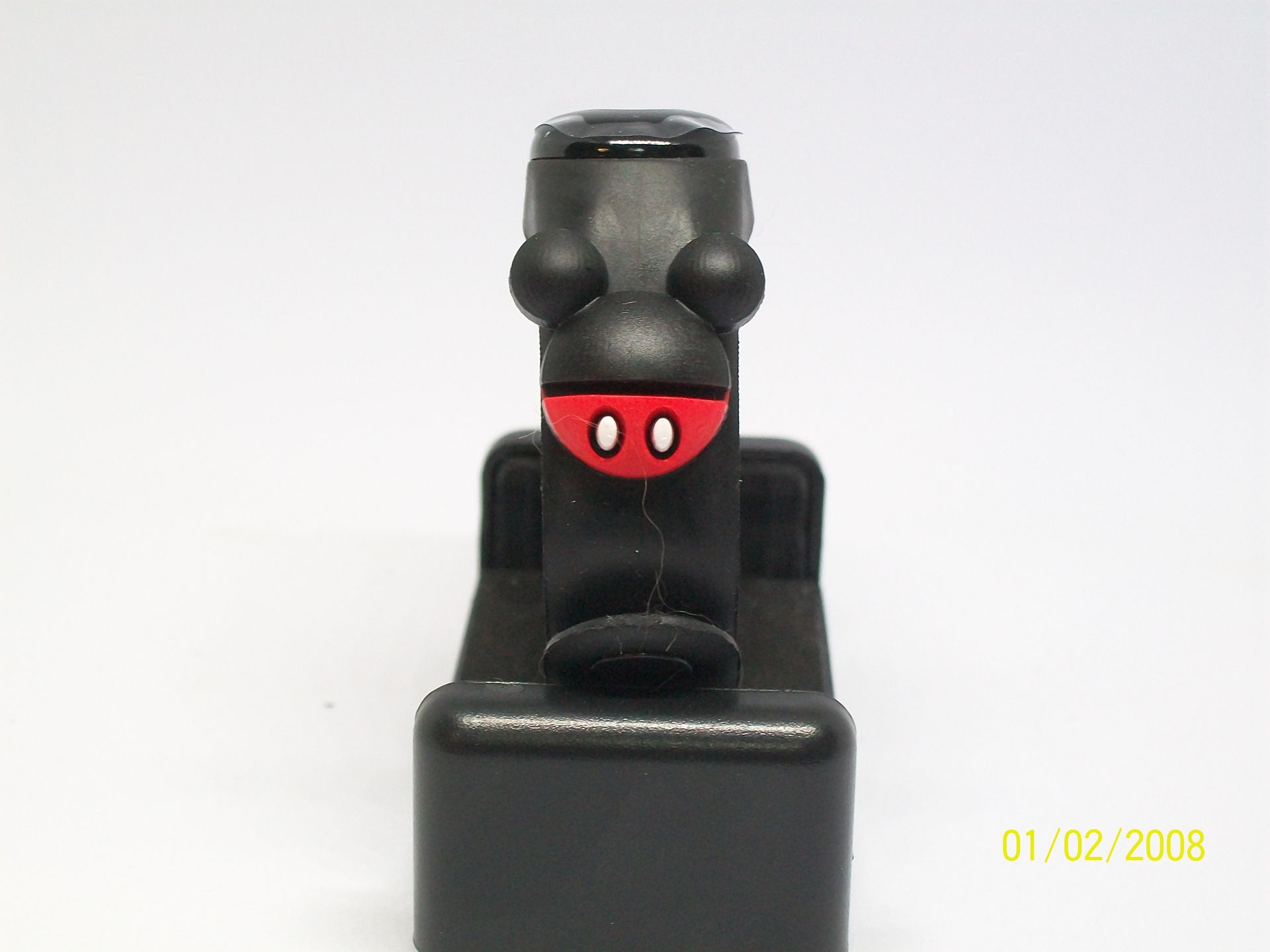 Zwarte fitnesstracker op een rode Sigma-lenshouder met een klein rood-wit bedeltje.