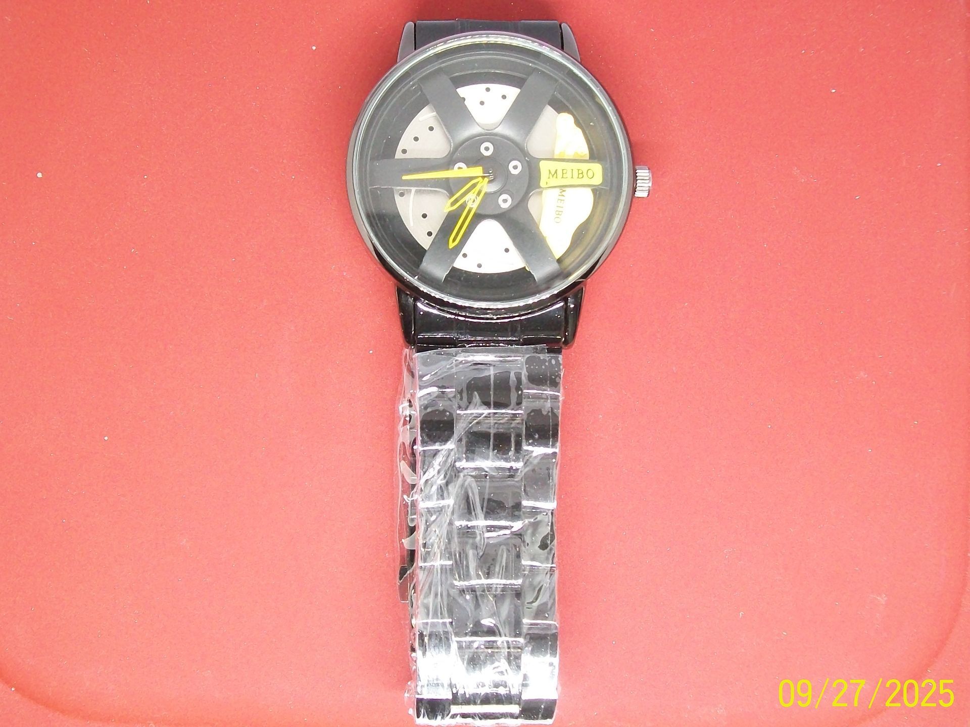 Zwart en zilverkleurig horloge met een autowielontwerp, gele accenten en een zwarte band.