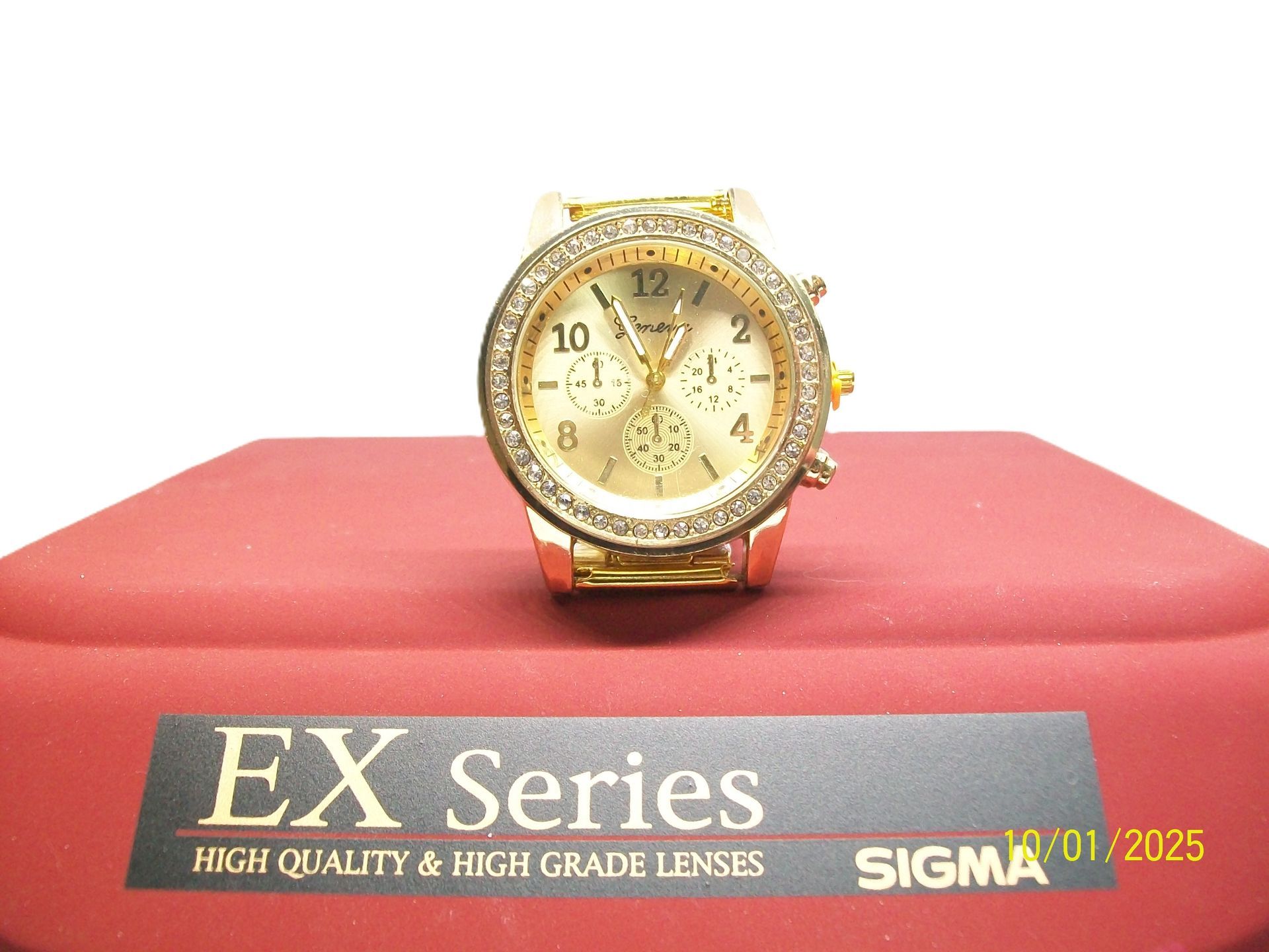 Gouden horloge met strass-steentjes op een rood platform. Onderaan de tekst "EX Series".