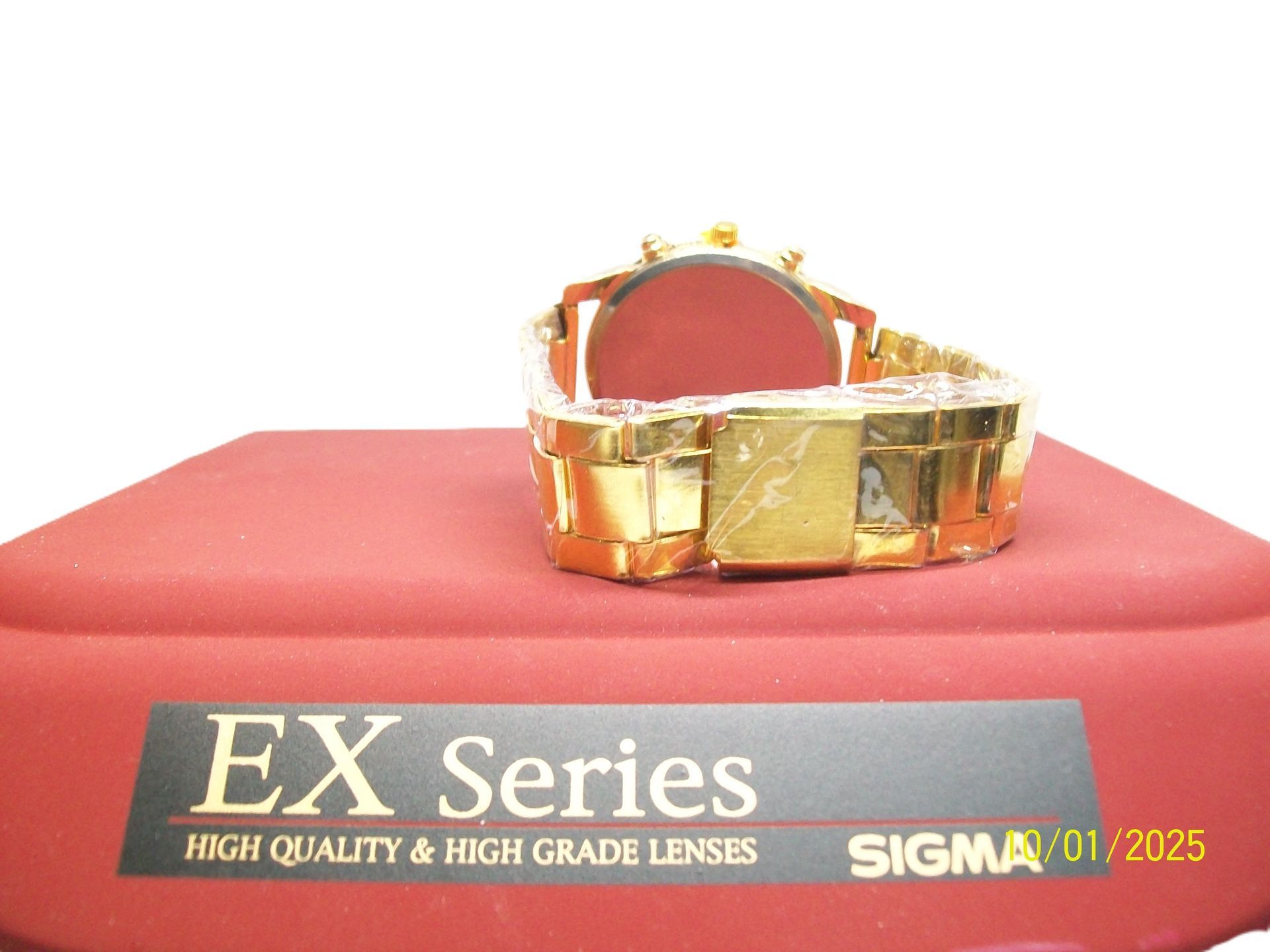 Gouden horloge met een diamanten lunette op een rood oppervlak, 