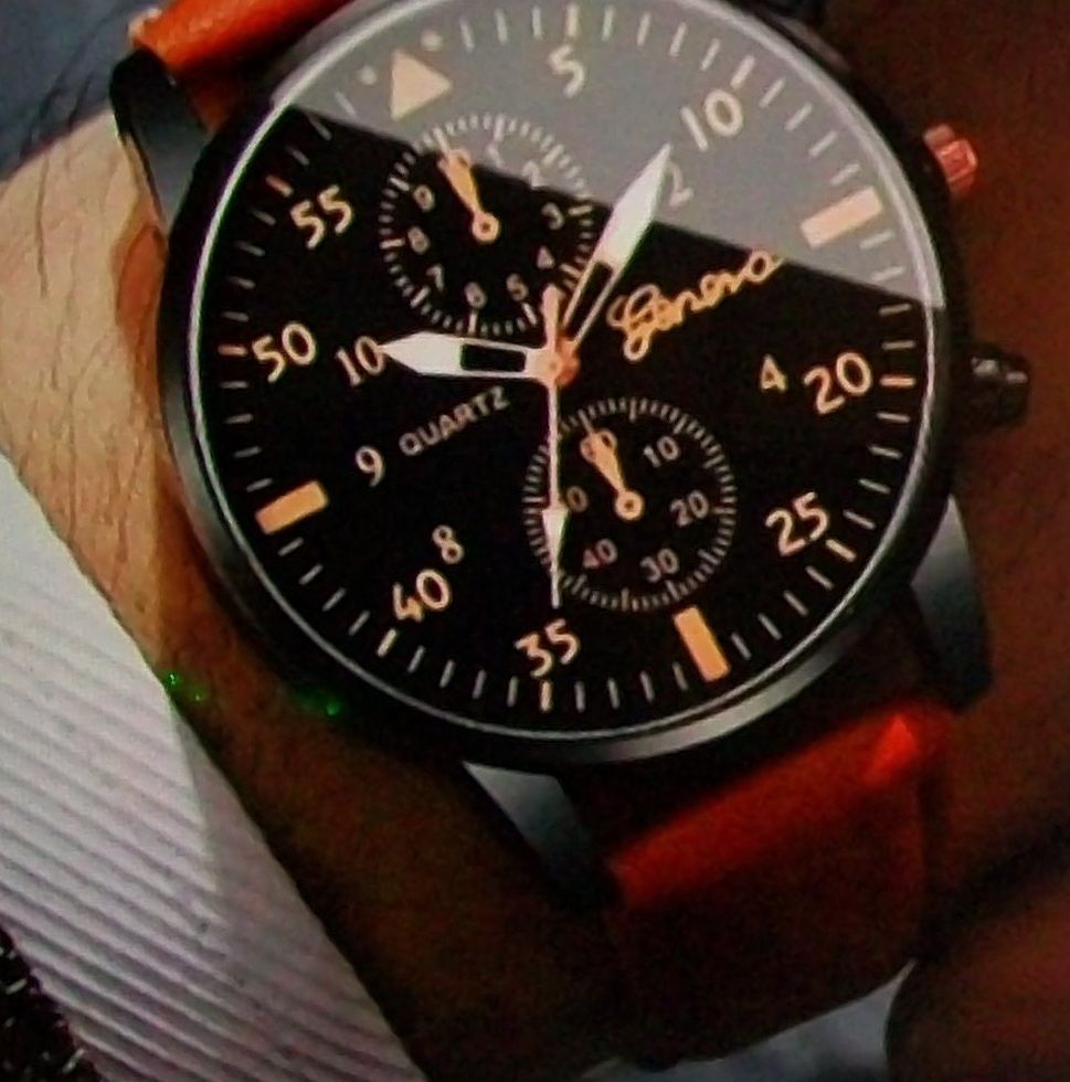 Een zwart Genève quartzhorloge met roségouden accenten op de pols.